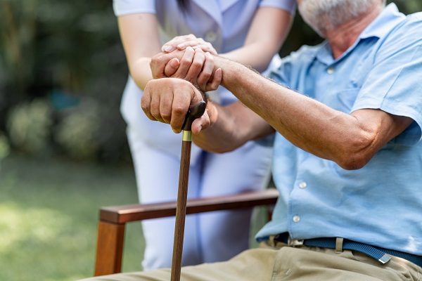 Man seated with younger woman putting her hands on his